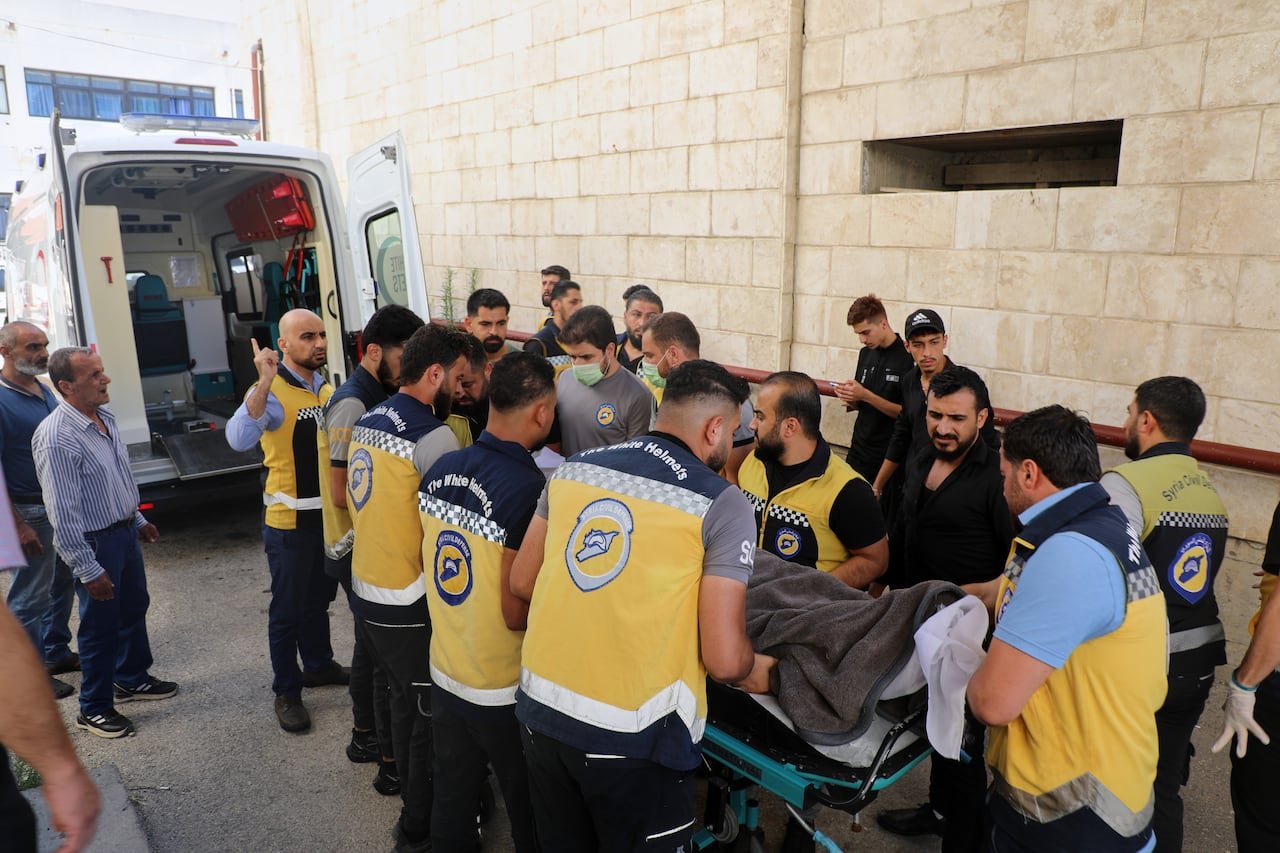 default-1562 Civil defence volunteer members gather around a body of someone on a stretcher.