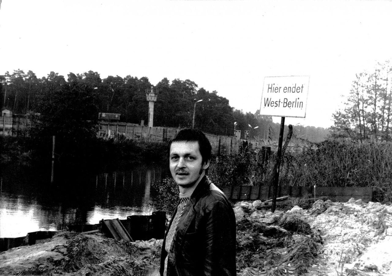 default-406 A man stands in front of the Spree river in black and white, with the Berlin wall behind him.