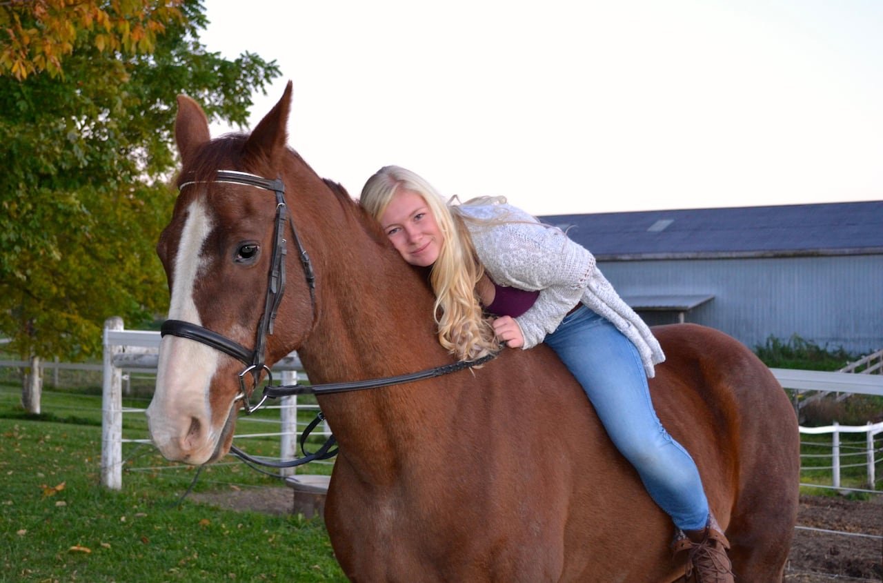 default-79 A woman sitting bareback on a horse bends down to hug it.