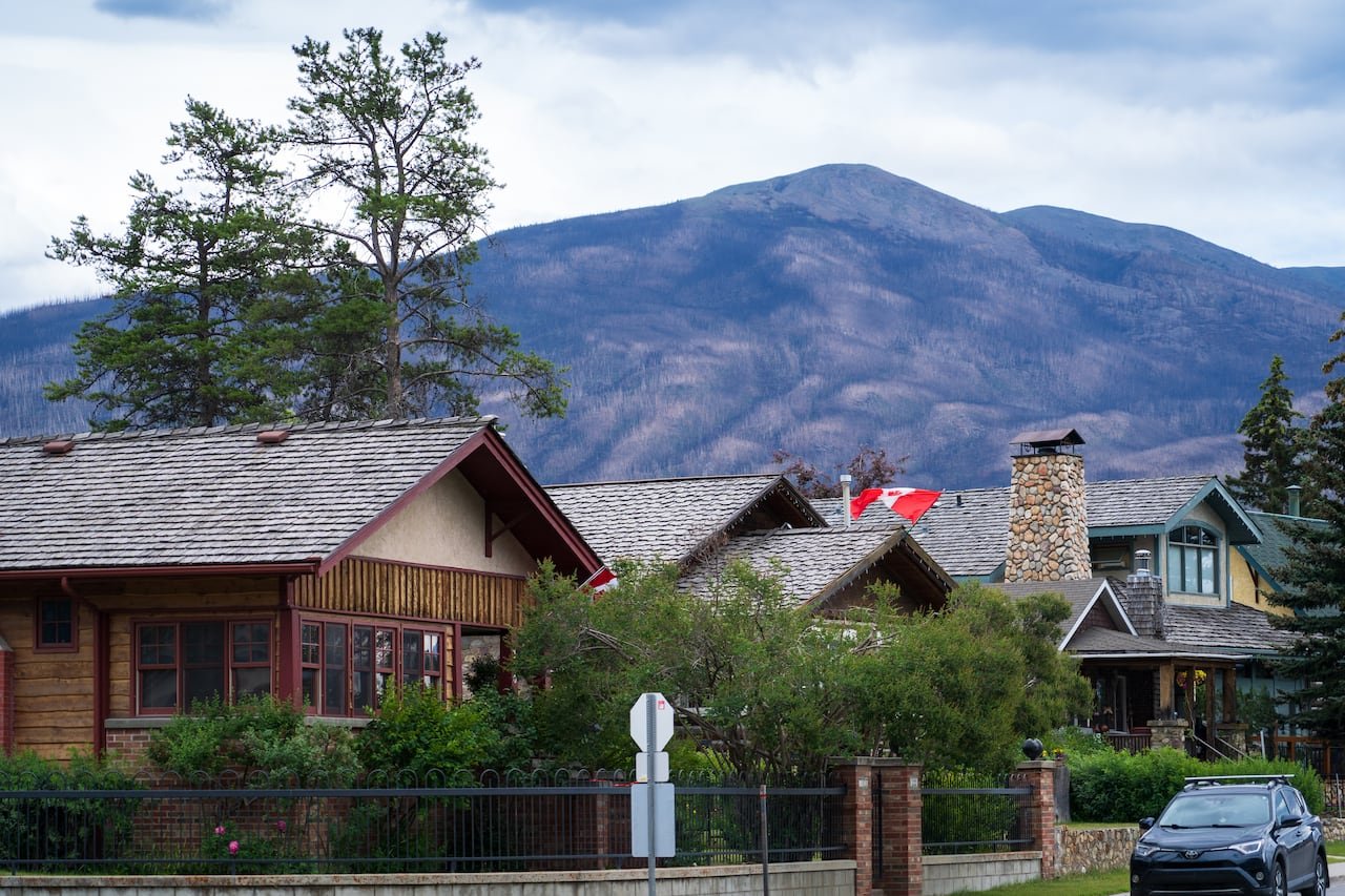 default-869 Three two-storey homes with cedar-shingled roofs sit in the foreground of a mountain backdrop in the Jasper townsite.